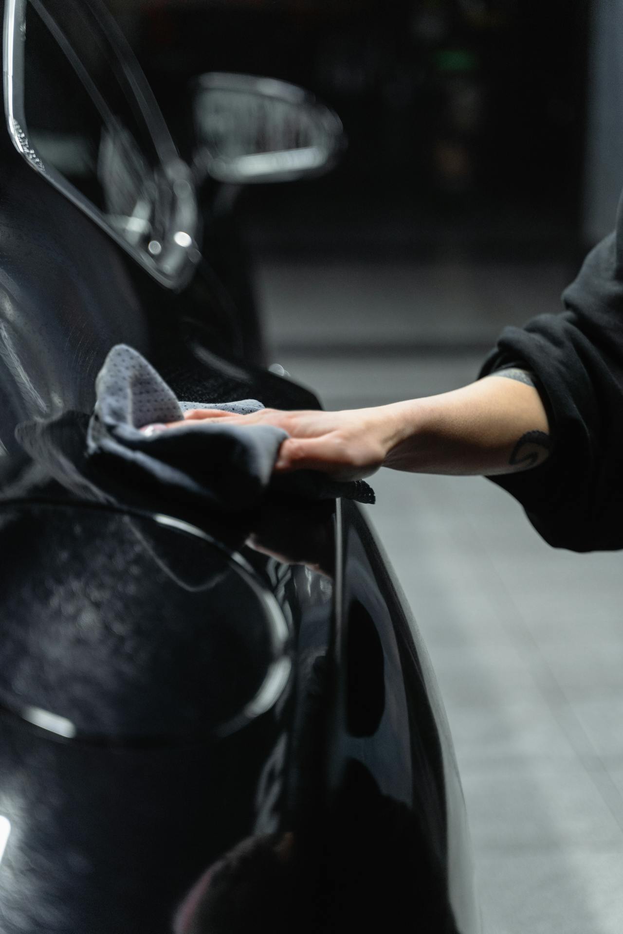 A Person Wiping a Car with a Cleaning Cloth<br />